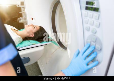 Il tecnico di scansione TC si affaccia sul paziente nello scanner di tomografia computerizzata durante la preparazione della procedura. Paziente donna che entra nello scanner TC. Foto Stock