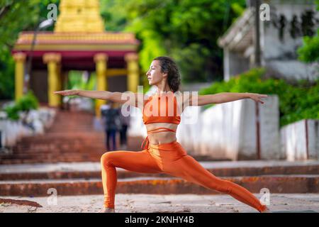 Una vista panoramica di una donna caucasica che fa yoga posa all'interno di un tempio indiano Foto Stock