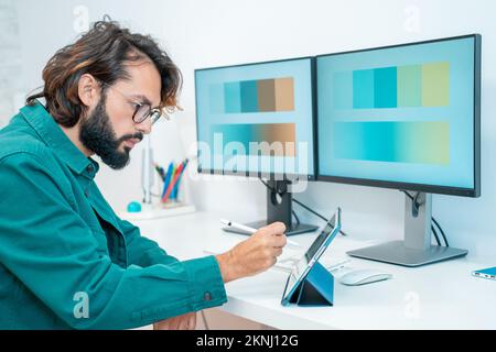 Graphic designer che lavora con computer tablet digitale penna stilo smartphone in ufficio moderno. Foto Stock