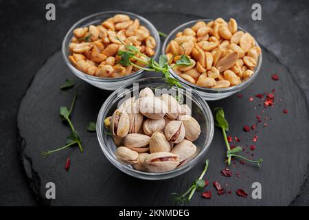 Noci salate, pistacchi e arachidi, per la birra, su fondo scuro Foto Stock