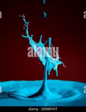 gocce di latte che collidono figure formate con lo sfondo rosso e le gocce di fotografia di colore blu di sfondi d'acqua Foto Stock