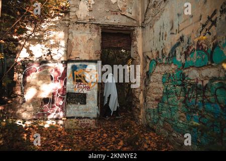 Una divertente immagine dell'uomo in costumi fantasma e occhiali da sole in un edificio abbandonato Foto Stock