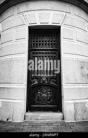 Una foto verticale di una vecchia porta con sculture in scala di grigi Foto Stock