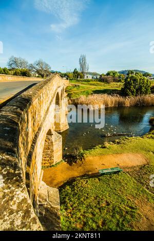 Sfondo verticale di un vecchio ponte in pietra che attraversa un tranquillo e lussureggiante paesaggio della Tasmania. Richmond Bridge, Australia Foto Stock