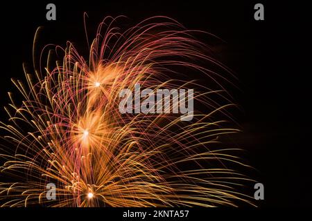 Fuochi d'artificio rossi, oro e bianchi nel cielo notturno. Foto Stock