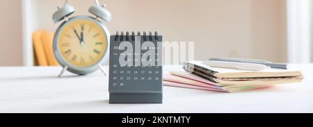 Calendario a fogli mobili con sveglia e notebook sul tavolo Foto Stock