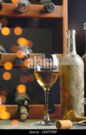 Bottiglie e bicchiere di vino a tavola in cantina Foto Stock