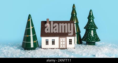 Alberi di Natale in ceramica, casa dei giocattoli e neve su sfondo azzurro Foto Stock