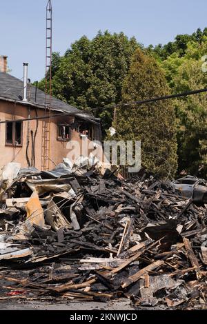 Fuoco danneggiato casa stile cottage vicino ai resti di edificio commerciale bruciato. Foto Stock