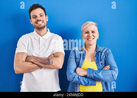 Giovane madre brasiliana e figlio in piedi su sfondo blu felice volto sorridente con braccia incrociate guardando la macchina fotografica. persona positiva. Foto Stock
