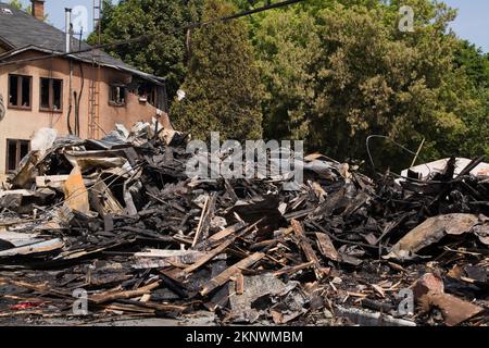 Fuoco danneggiato casa stile cottage vicino ai resti di edificio commerciale bruciato. Foto Stock