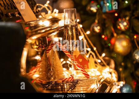 Bicchiere di champagne con decorazioni natalizie e luci accese su chiavi del piano, guardaroba Foto Stock