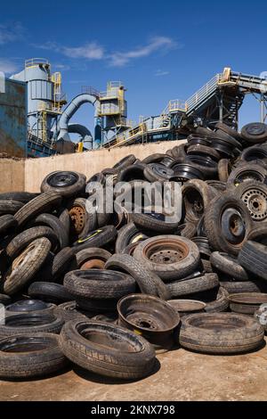 Cumulo di pneumatici per autocarri scartati nel contenitore presso il deposito di riciclaggio dei rottami metallici. Foto Stock