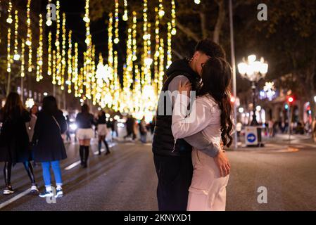 Barcellona, Spagna. 26th Nov 2022. Una giovane coppia bacia sotto le luci di Natale in via Passeig de gracia. L'amministrazione cittadina di Barcellona ha ridotto il numero di luci e i tempi di illuminazione a causa dell'aumento dei costi energetici causati dalla guerra Russia-Ucraina. Credit: SOPA Images Limited/Alamy Live News Foto Stock