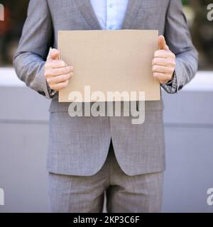 Assumi e Ill diffonde il vostro messaggio per voi. un uomo d'affari che tiene un cartello vuoto per strada. Foto Stock
