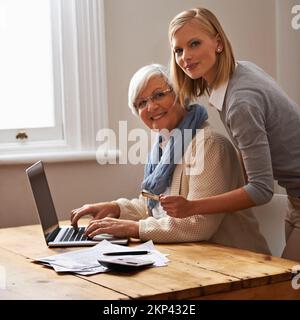 Prestito di una mano con le dichiarazioni di imposta di Grandmas. Una nipote che aiuta la nonna con il suo budget. Foto Stock