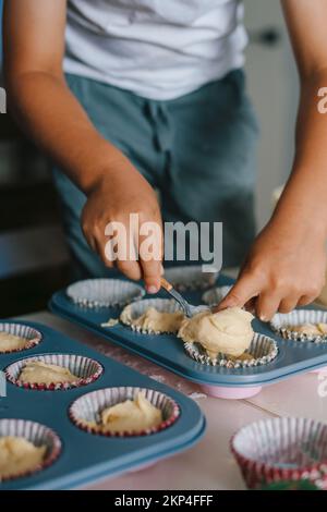 Mescolare tutti gli ingredienti, preparare l'impasto o la pastella e riempire la forma di cottura della carta. Versare l'impasto per muffin negli stampi. Cupcake Foto Stock