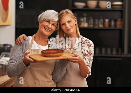 Incollaggio su prodotti da forno. una bella giovane donna e sua nonna mostrando le loro capacità di cottura. Foto Stock