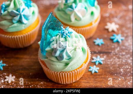 Cupcake fatto in casa di colore blu collocato su una scrivania di legno. Tema invernale e natalizio, fiocchi di neve al gelato blu. Dolce fresco e cotto in casa. Foto Stock