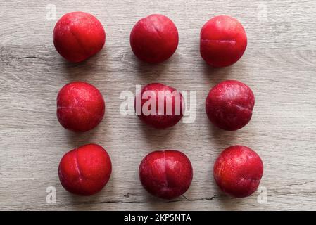 Prugne fresche isolate su fondo tavolo in legno Foto Stock