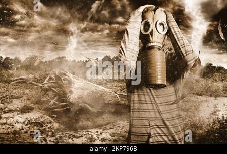 Ritratto creativo di un uomo stanco in piedi in una terra desolata barone con maschera di gas strappata dalla guerra che guarda ai cieli di terrore e vapori tossici. La caduta Foto Stock