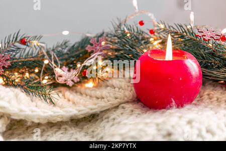 Composizione natalizia con candela, elemento a maglia con rami di abete. Foto Stock