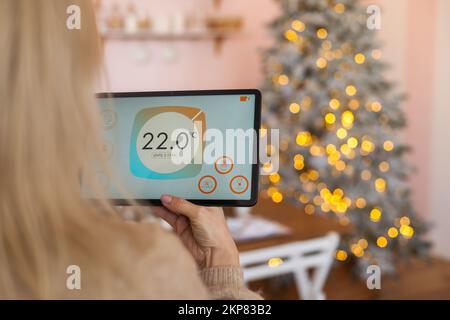 Moderna app di automazione domestica intelligente sul display del tablet nelle mani di una donna a Natale Foto Stock