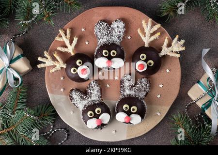 Delizie fai da te per il capodanno per bambini, coniglietti e cervi da biscotti, marshmallows, cioccolato e fiocchi di cocco, vista dall'alto Foto Stock