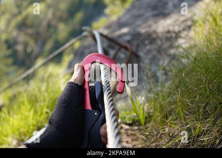 mettere un moschettone su un corda metallica su una via ferrata nelle alpi austriache. Foto Stock