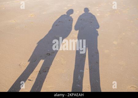 Un'ombra di due persone su una spiaggia. Foto Stock