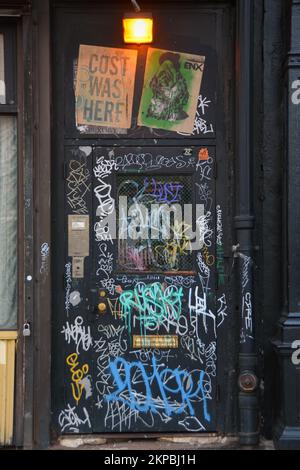 Un collage di tagging, segni e graffiti su una porta sul lato Lower East di Manhattan, New York City. Foto Stock