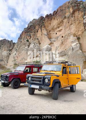 Due SUV 4x4 (Sports Utility Vehicle) parcheggiati di fronte al monumento a Ortahisar, Cappadocia, Turchia, presi dalla vista laterale Foto Stock