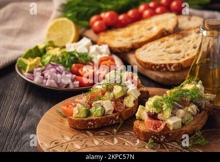 Gustosi e sani avocado, pomodori ciliegini e sandwich al formaggio feta. Tostatura con avocado, pomodori e feta. Foto Stock