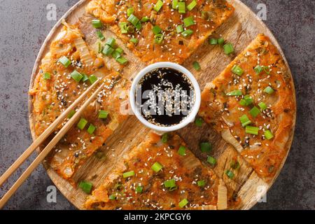 Kimchi-buchimgae o kimchijeon fatto con kimchi affettati, pastella di farina e a volte altri ortaggi primo piano sul legno tavola. Horizont Foto Stock