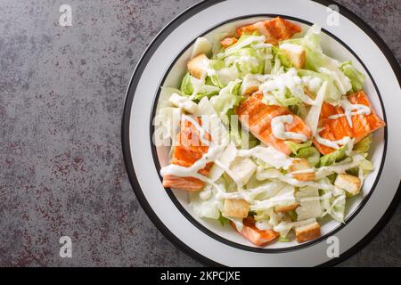 Insalata Caesar di salmone alla griglia con crostini, parmigiano, condimento Caesar primo piano sul piatto sul tavolo. Vista orizzontale dall'alto Foto Stock