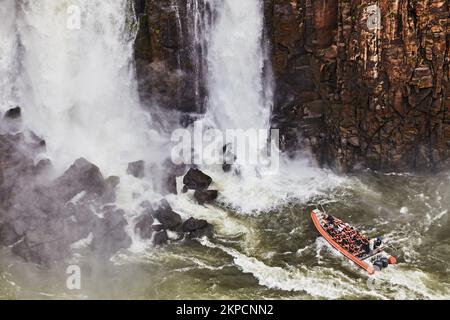 Popolare attività di avventura turistica alle Cascate di Iguazu, il motoscafo si avvicina al torrente d'acqua, vista dal lato brasiliano Foto Stock