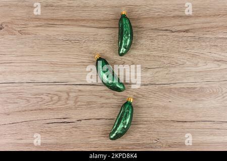 Tre baubles dell'albero di Natale nella forma di un cetriolo sono sdraiati su un fondo di legno. Foto Stock