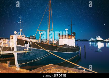 Helsinki, Finlandia. Cielo stellato blu brillante. Vista di Fishing Marine Boat, motoscafo al molo in notturna illuminazioni. Azzurro cielo drammatico Foto Stock