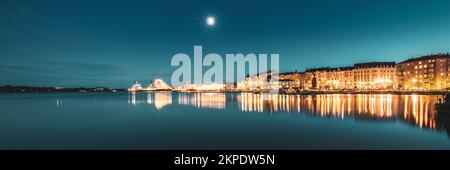 Helsinki, Finlandia. Cielo stellato blu brillante. Vista del porto di polizia Merikasarmin Laituri e della strada di Laivastokatu nelle illuminazioni notturne. Luce Foto Stock