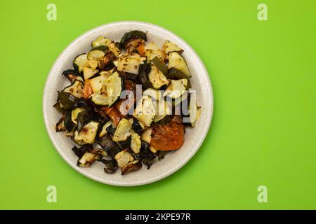 Verdure al forno miste su piatto marrone chiaro sul verde Foto Stock