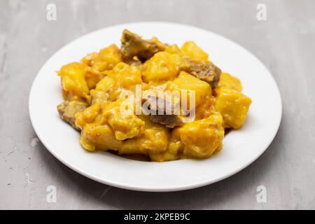 Stufato di manzo con patate dolci e salsa al curry su piatto bianco Foto Stock