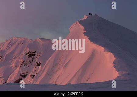 Persone in cima circondate da cornici di neve e ripide piste ghiacciate, incontrando l'alba in montagna d'inverno. Marmaros gamma, i Carpazi Foto Stock