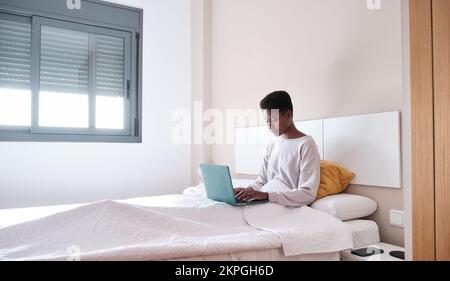 Ha concentrato la freelance femminile che lavora al computer in camera da letto Foto Stock