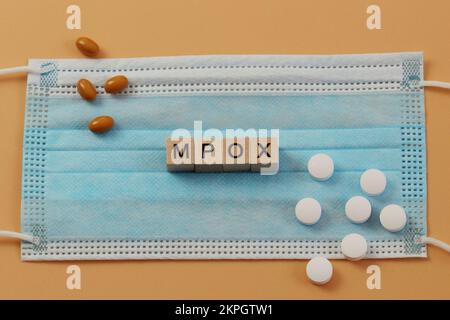 Mpox è disposto con cubi di legno su una maschera chirurgica. Ci sono varie pillole che si trovano intorno. MPOX è il nuovo nome per il virus monkeypox. Foto Stock