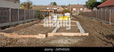 Calcestruzzo misto pronto pompato trasportato da tubo dalla strada direttamente in riempimento di trincea fondamenta di fondazione della casa indipendente Essex Inghilterra UK Foto Stock