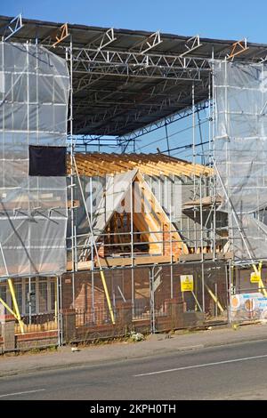 Lavori di costruzione in cantiere modifiche di miglioramento della casa che richiedono travi temporanee del tetto e ponteggi ad accesso laterale con protezione contro le intemperie Inghilterra UK Foto Stock