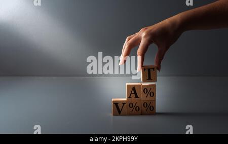 posa a mano di blocchi di legno con iva o imposta sul valore aggiunto . concetto di pagamento delle tasse , su sfondo grigio . Foto Stock