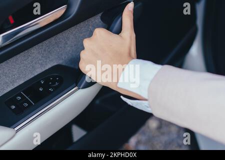 Primo piano della mano di una giovane donna che chiude le porte di un'auto. Foto Stock