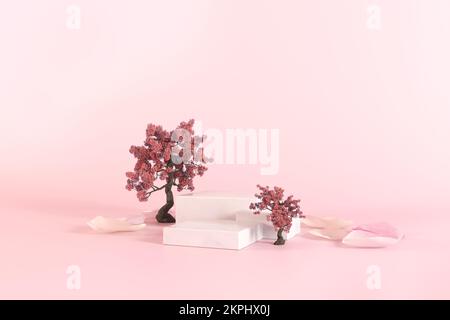Rosa mockup delicato con tre podi bianchi per mostrare il prodotto cosmetico con albero sakura, petali di fiori e morbido sfondo rosa pastello chiaro Foto Stock