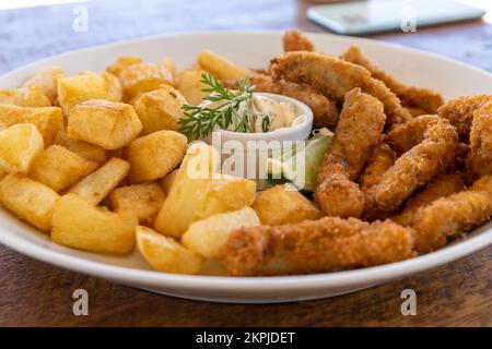 Manioca e pesce fritto su un piatto. Cibo ad alto valore calorico. Foto Stock